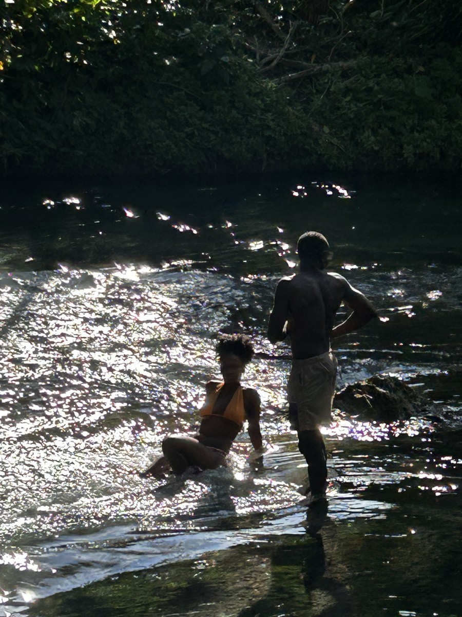 Backlit, two figures in the sparkling shallows at the end of the day
