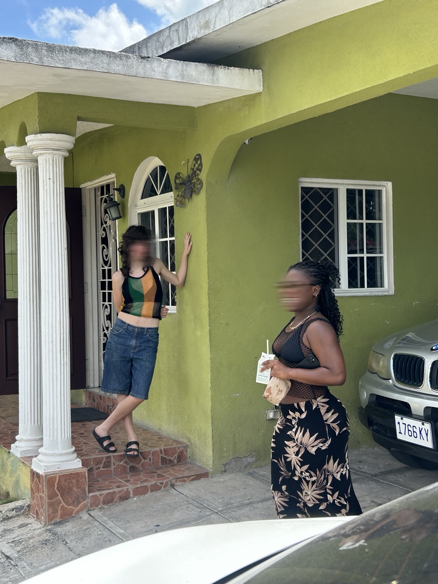 Two friends outside a green house in Red Hills, faces motion-blurred