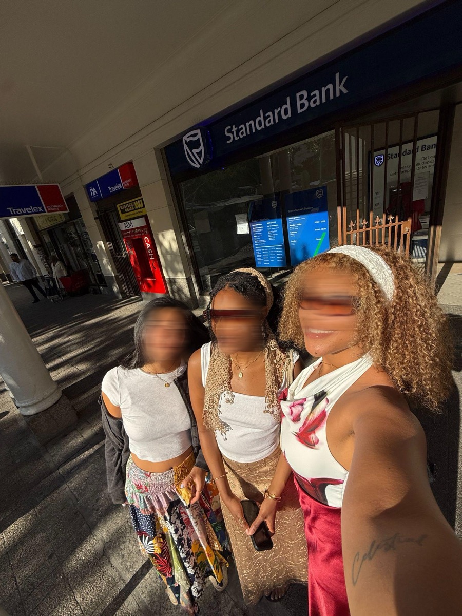 Three friends together on the pavement outside the bank, all three faces motion-blurred